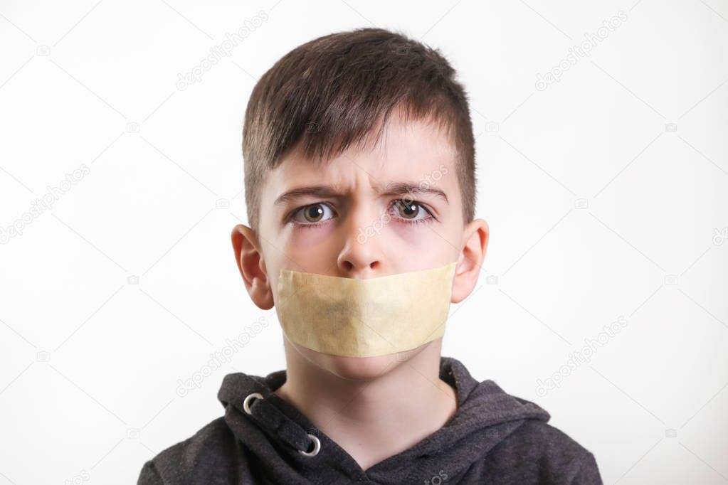 Studio portrait of young boy with adhesive tape over his mouth