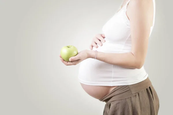 青リンゴ スタジオ ショットを保持している妊娠中の女性 — ストック写真