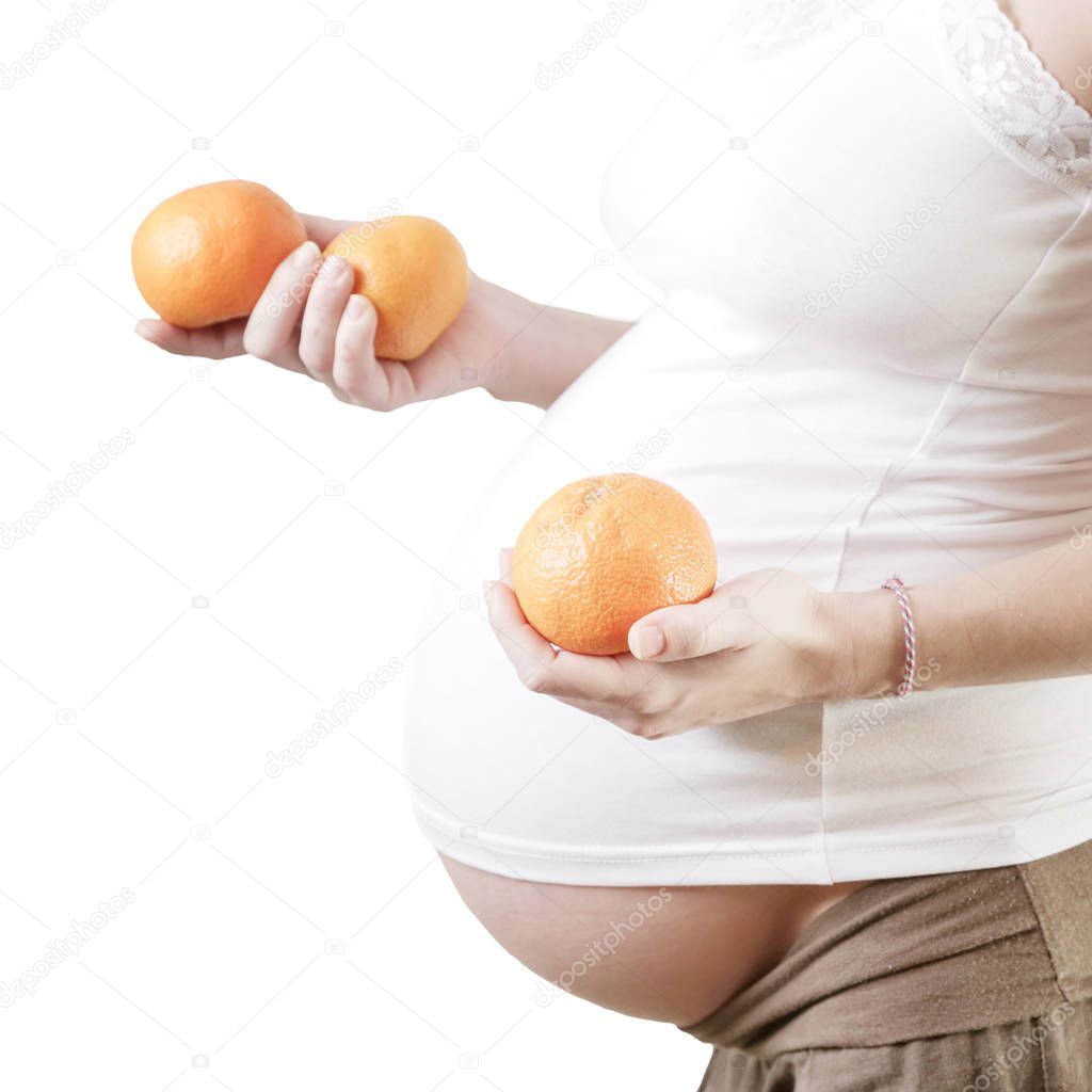 Pregnant woman holding oranges - studio shot