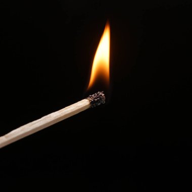 An igniting match against black background clipart