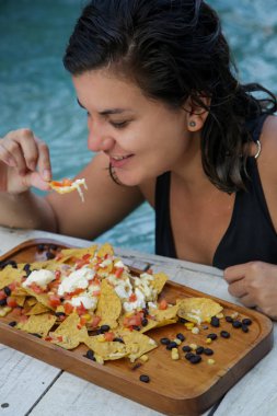 Havuzun yanında, sağlıklı yaşam konsepti cips yeme güzel genç kadın