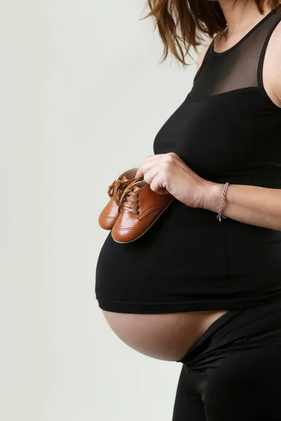 妊娠中の女性は彼女の赤ん坊のための靴を保持 — ストック写真