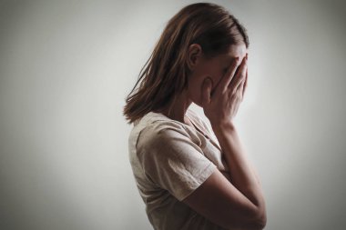 Yüzünü elleri yan görünüm kapsayan depresif kadın portresi