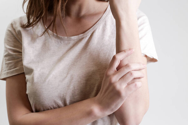 Close up view of woman scratching her arm. Health care and medical concept.