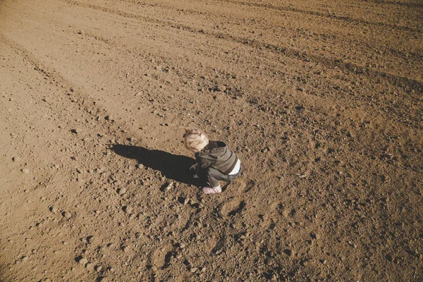 Милая девочка, играющая с грязью на плоском участке сельскохозяйственного участка. — стоковое фото