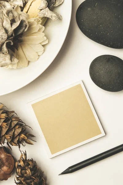 Cartão castanho em branco com pedras zen e flores secas na mesa — Fotografia de Stock