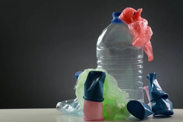 Single-use plastic bottles, cups and bags, studio shot. Plastic pollution concept.