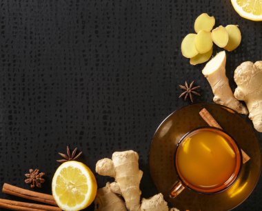Karanlık arka planda zencefil kökleri ve limon ile bir bardak zencefil çayı. Sağlıklı bir yaşam tarzı, Anti-grip ve anti-inflamatuar kavramı.