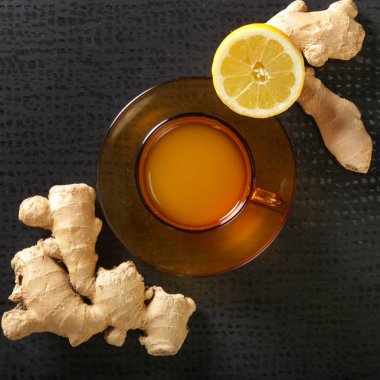 Karanlık arka planda zencefil kökleri ve limon ile bir bardak zencefil çayı. Sağlıklı bir yaşam tarzı, Anti-grip ve anti-inflamatuar kavramı.