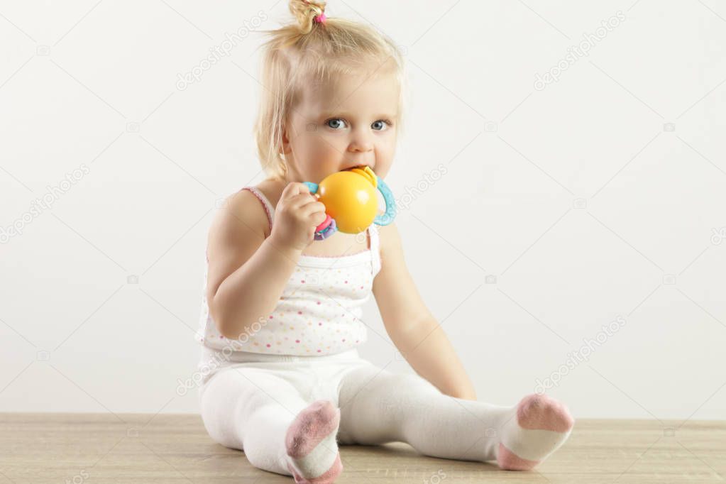 An adorable baby girl chewing a teething toy to relieve sore and sensitive gums.