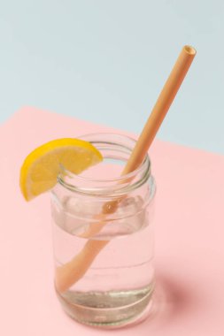 Pembe arka plan üzerinde limon su bir bardak Bambu saman, tek kullanımlık plastik pipetler, sağlıklı ve sürdürülebilir yaşam tarzı kavramı için bir alternatif olarak yeniden kullanılabilir bambu pipetler