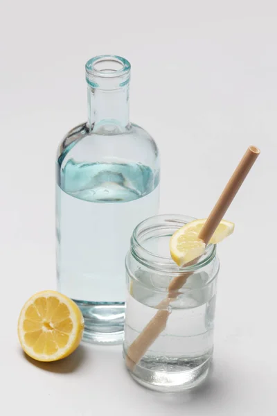 Bamboo straw in a glass of lemon water on the grey background, Reusable bamboo straws as an alternative for single-use plastic straws, healthy and sustainable lifestyle concept