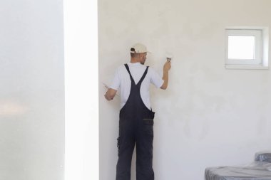 Macun bıçağıyla duvar ören adam, görüntüyü kapatın. Duvar yüzeyinin sabitlenmesi ve boyama için hazırlık.