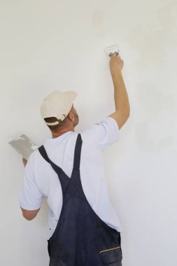 Macun bıçağıyla duvar ören adam, görüntüyü kapatın. Duvar yüzeyinin sabitlenmesi ve boyama için hazırlık.