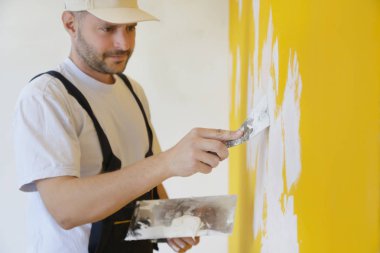 Macun bıçağıyla duvar ören adam, görüntüyü kapatın. Duvar yüzeyinin sabitlenmesi ve boyama için hazırlık.