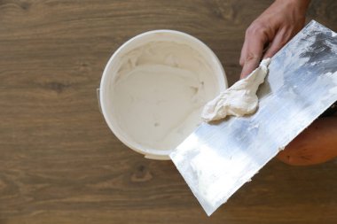 Macun bıçağıyla duvar ören adam, görüntüyü kapatın. Duvar yüzeyinin sabitlenmesi ve boyama için hazırlık.