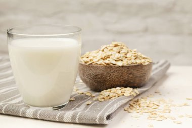 Yulaf sütü ve yulaf haddelenmiş. Bir bardakta organik vegan süt bitkisi bazlı olmayan süt.