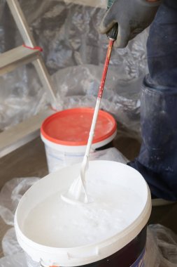 Adam iç duvarlar için beyaz boya hazırlanıyor