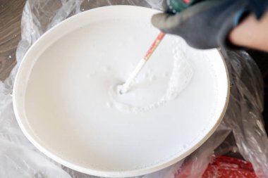 Adam iç duvarlar için beyaz boya hazırlanıyor