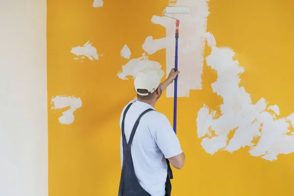 Человек Рисует Белой Краской Над Жёлтой Стеной — стоковое фото