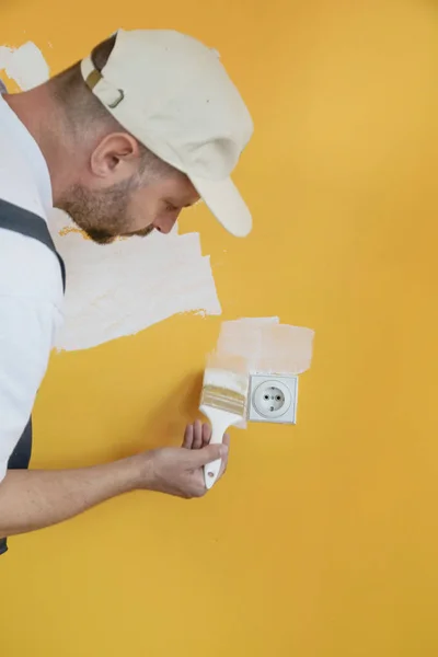 Живопись Белой Краской Над Жёлтой Стеной — стоковое фото
