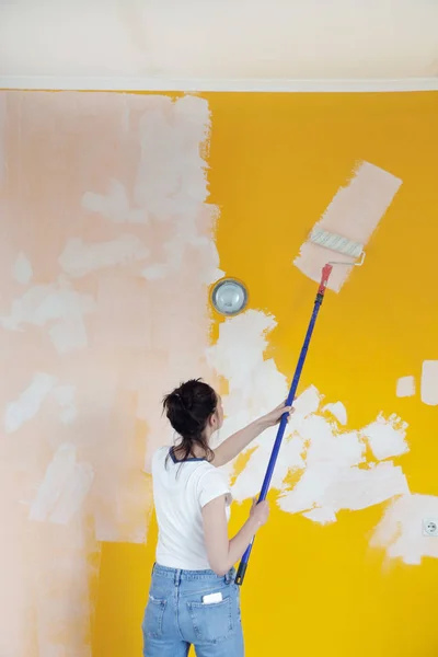 Γυναίκα Ζωγραφική Λευκό Χρώμα Πάνω Από Ένα Κίτρινο Τοίχο — Φωτογραφία Αρχείου