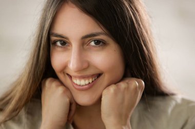 Kameraya gülümseyen doğal güzel genç bir kadının stüdyo portresikadar yakın