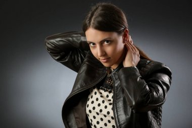 Koyu zemin üzerinde siyah deri ceket giyen genç bir kadının Stüdyo portresi