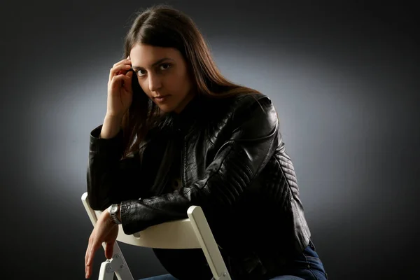 一个年轻女子穿着黑色皮夹克在深色背景的工作室肖像 — 图库照片