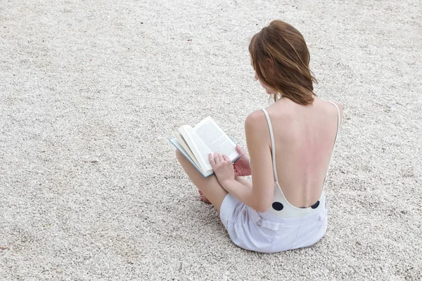 读一本书在海滩上的年轻女子 — 图库照片