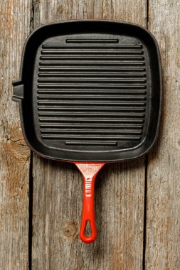 Ahşap arka plan üzerinde kırmızı emaye demir tencere üst görünümü