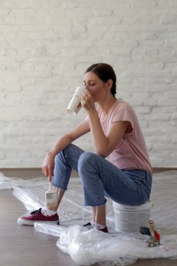 Genç bir kadın evini dekore ederken kahve molası veriyor. Büyük işten önce dinleniyor.