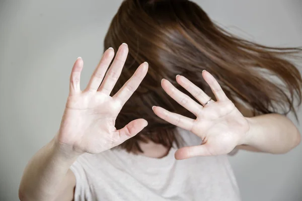 Self defense, studio portrait of scared woman raising hands up in defense