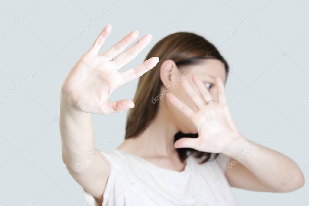 Self defense, studio portrait of scared woman raising hands up in defense