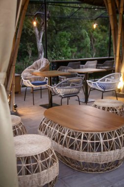 Akşam saatlerinde beyaz masalar ve rattan sandalyeile Cafe, rahat tarzı, hiçbir kişi