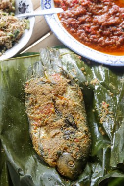 Geleneksel Endonezya mutfağı. Soslar ve garnitürler ile muz yaprağı üzerinde servis baharatlı ızgara balık 