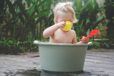 Plastik bir kova içinde bebek banyo, yaz gününde samimi açık portre