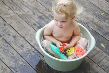 Plastik bir kova içinde bebek banyo, yaz gününde samimi açık portre