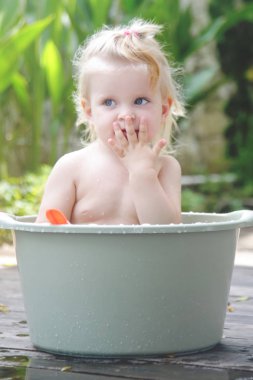 Plastik bir kova içinde bebek banyo, yaz gününde samimi açık portre
