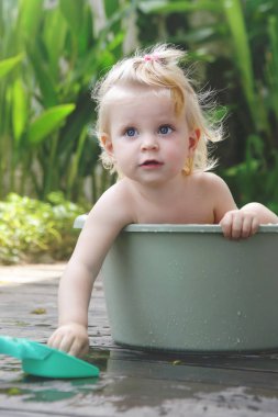 Plastik bir kova içinde bebek banyo, yaz gününde samimi açık portre