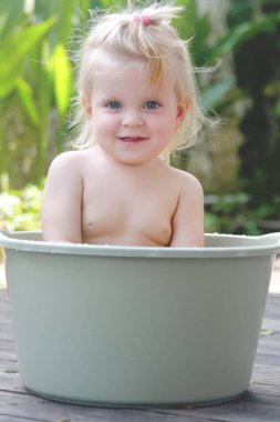 Plastik bir kova içinde bebek banyo, yaz gününde samimi açık portre