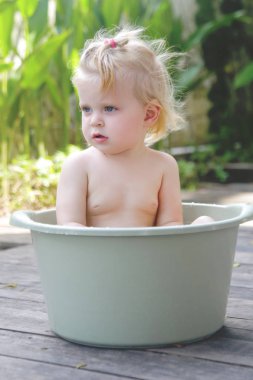Plastik bir kova içinde bebek banyo, yaz gününde samimi açık portre