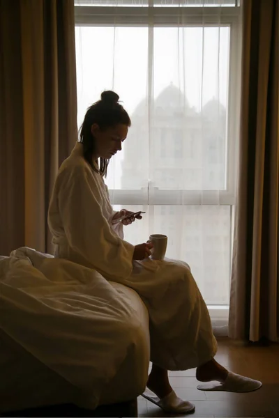 Woman drinking the first-morning coffee next to the window