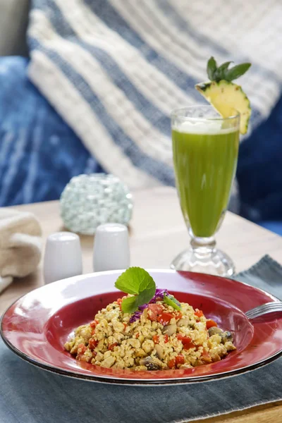 Simple tofu scramble, a vegan alternative to scrambled eggs with a fresh green organic smoothie served on the restaurant table, vegetarian healthy snack