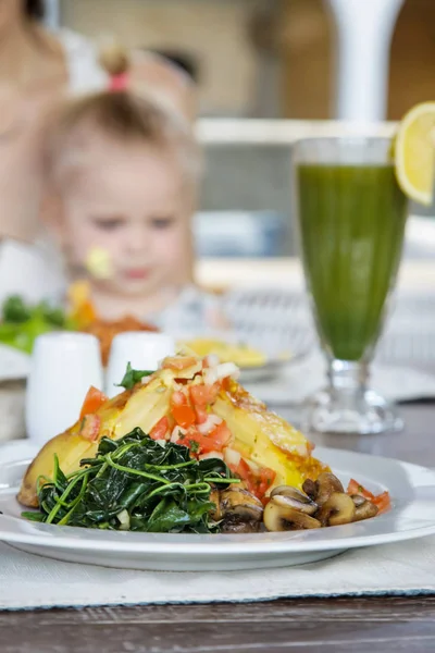 Spanish potato tortilla served with mushrooms, spinach and green detox drink on the wooden table, casual dining restaurant food