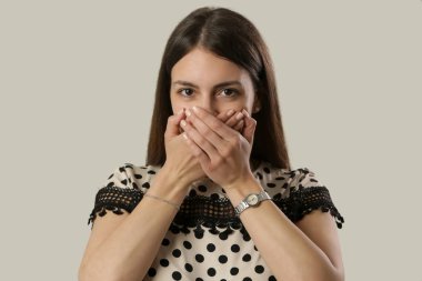 Elleri ile ağız kapsayan genç bir kadının Stüdyo portre, hiçbir dedikodu, hiçbir kötü kavram konuşmak