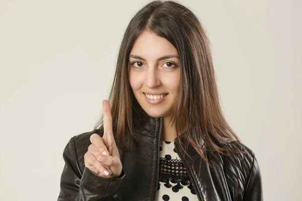 Retrato Uma Jovem Mulher Sorrindo Mostrando Dedo Indicador Tiro Estúdio — Fotografia de Stock