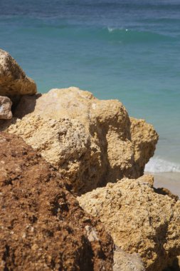 Arkasında turkuaz su ile sahilde büyük kayalar