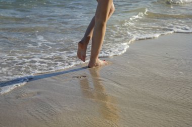 Kadın tropikal kumlu plajda yürüyüş, bacaklar ve dalgalar görüntü yakın
