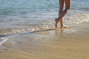 Kadın tropikal kumlu plajda yürüyüş, bacaklar ve dalgalar görüntü yakın